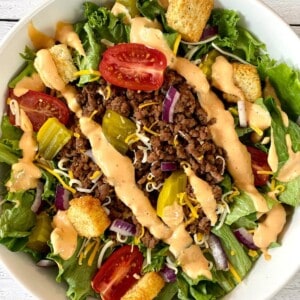 Big mac salad with pickles, tomatoes, onion, and thousand island dressing.