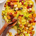 Warm Brussels sprouts salad with butternut squash, apples, cranberries, and bacon on a large serving platter.