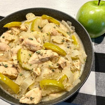 A bowl filled with this apple chicken recipe with an apple to the side.