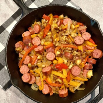 Simple Sausage Skillet with Onions, Peppers, and Potatoes in a cast iron skillet.