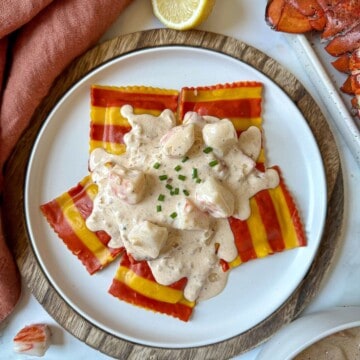 Sherry cream sauce for lobster ravioli on a plate with lobster pieces and lemon.