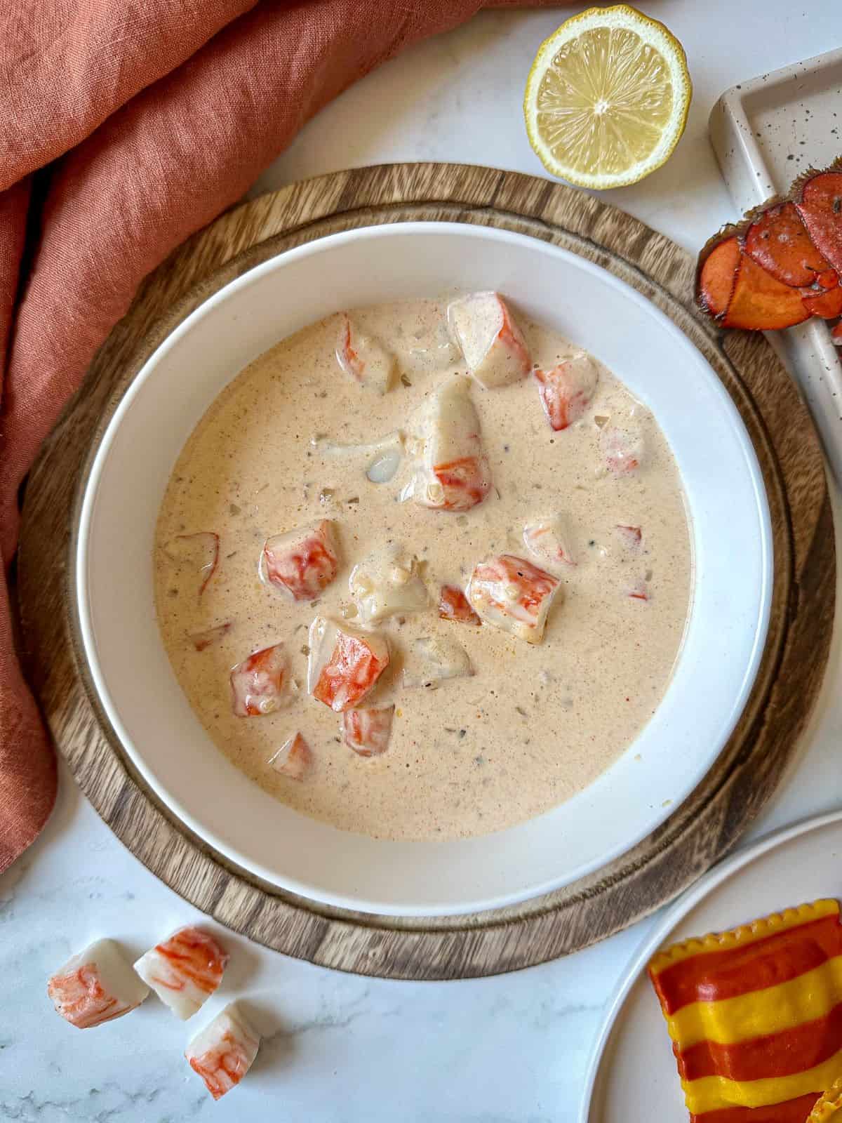 Sherry cream sauce for lobster ravioli in a bowl with pieces of lobster.