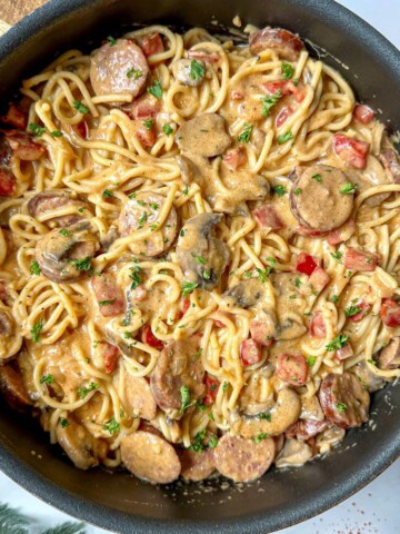 A skillet of creamy Cajun spaghetti sauce with sausage, peppers, and mushrooms.