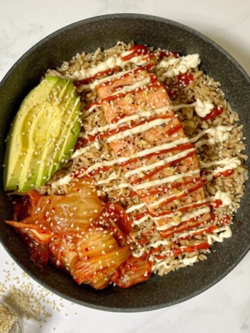 Spicy Salmon Bowl with Kimchi and Avocado sprinkled with sesame seeds.