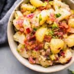 German Potato Salad combines tender potatoes with a warm bacon-mustard vinaigrette dressing in a bowl.