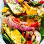 A variety of marinated grilled vegetables with herbs sprinkled on top.