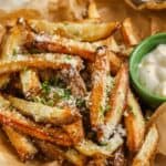 Air fryer French fries topped with parmesan and chives with a bowl of dipping sauce on the side.