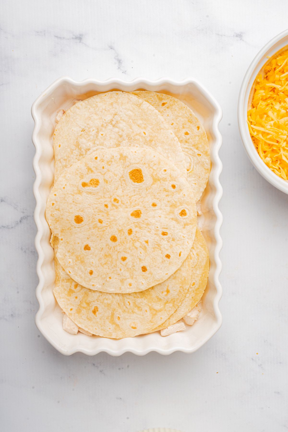 A layer of corn tortillas in a large casserole dish.