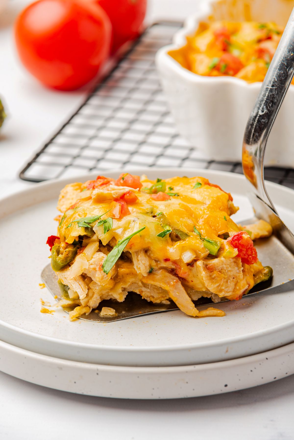 A serving of king ranch chicken casserole with Rotel and cheese on a spatula on top of a white plate.