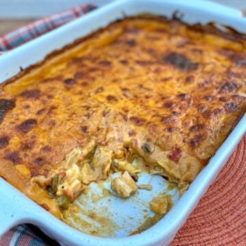 King Ranch Chicken Casserole in a large baking dish with a scoop taken out exposing chicken, veggies, and sauce on the inside.