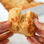 Hands are pulling apart a biscuit showing the fluffy inside.