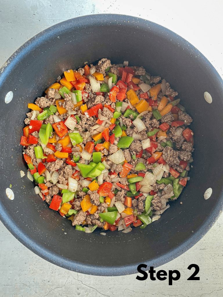 Ground beef and vegetables sautéing in a large Dutch oven pot.
