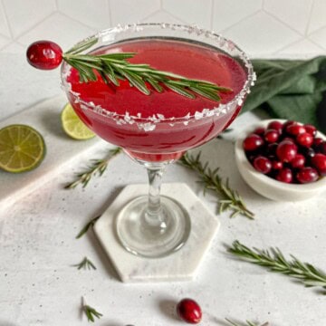 Christmas margarita cocktail with tequila and a garnish of fresh rosemary.