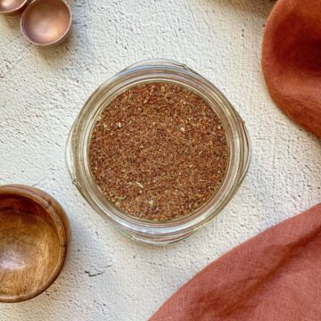 Homemade taco seasoning in a mason jar with measuring spoons on the side.