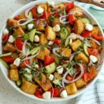 Colorful panzanella salad in a bowl with bread and tomatoes.