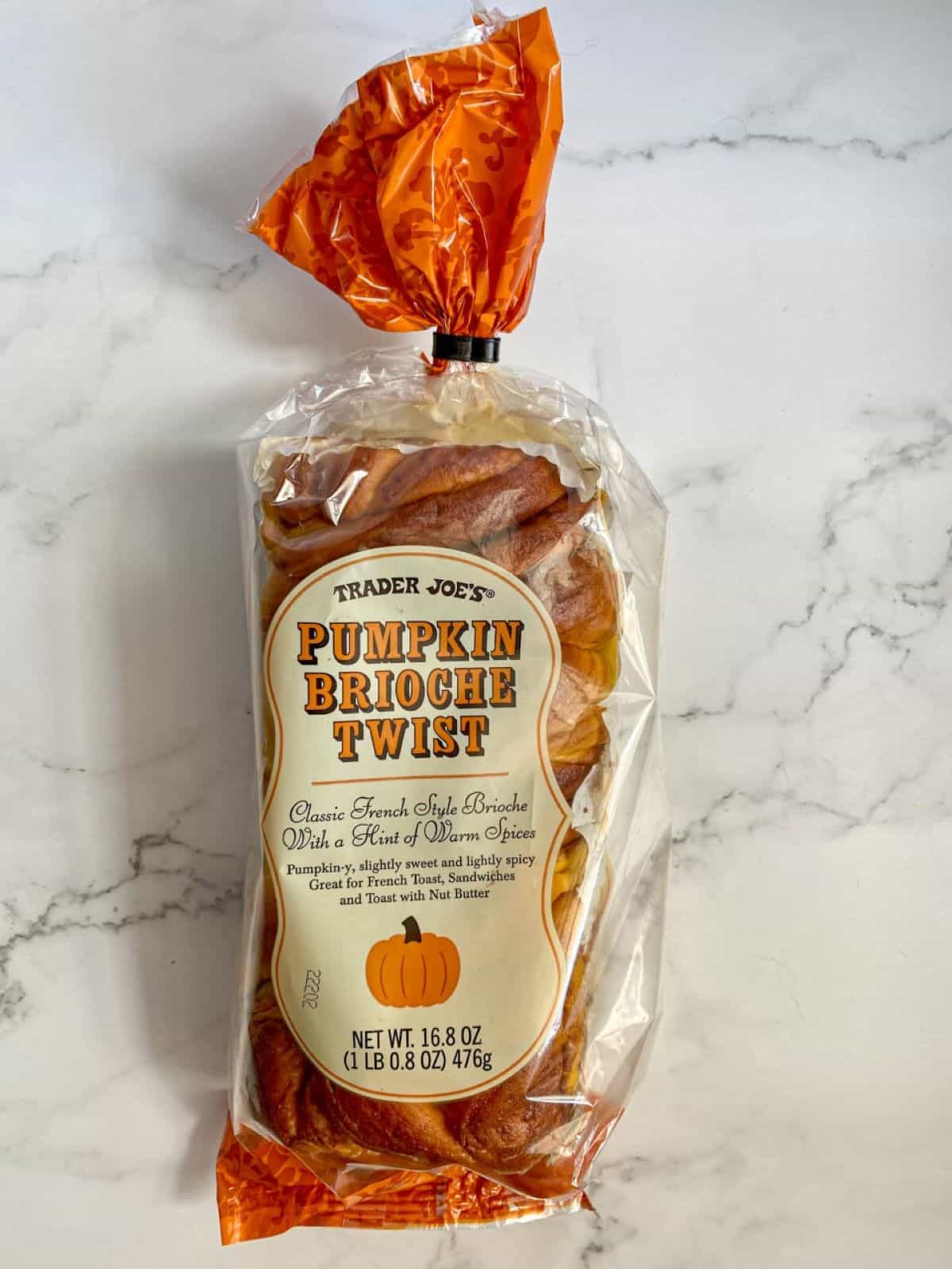 A loaf of Trader Joe's Pumpkin Brioche Twist bread is an a marble table.