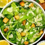 Classic Caesar salad in a white bowl with creamy dressing and croutons.
