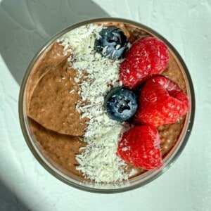 Chocolate Chia Seed Pudding in a bowl with fresh berries and shredded coconut flakes.