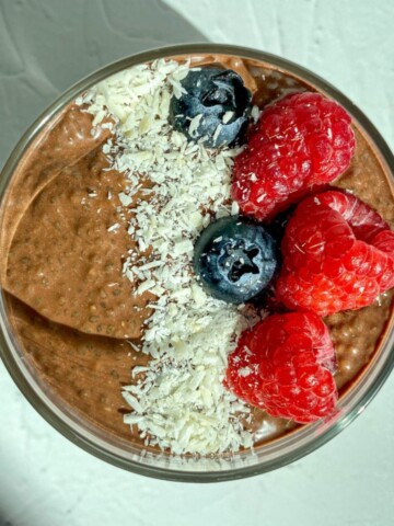 Chocolate Chia Seed Pudding in a bowl with fresh berries and shredded coconut flakes.