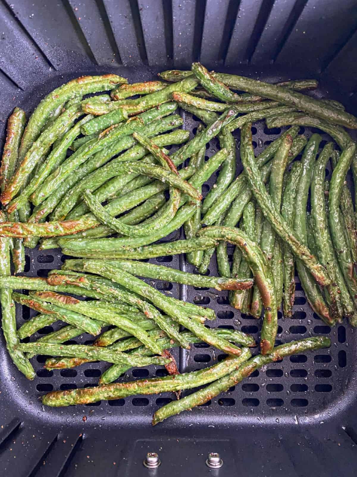 Cooked green beans in air fryer basket.