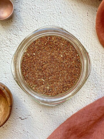 Homemade taco seasoning in a mason jar with measuring spoons on the side.