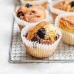 Air fryer muffins with blueberries are cooling on a wire rack.
