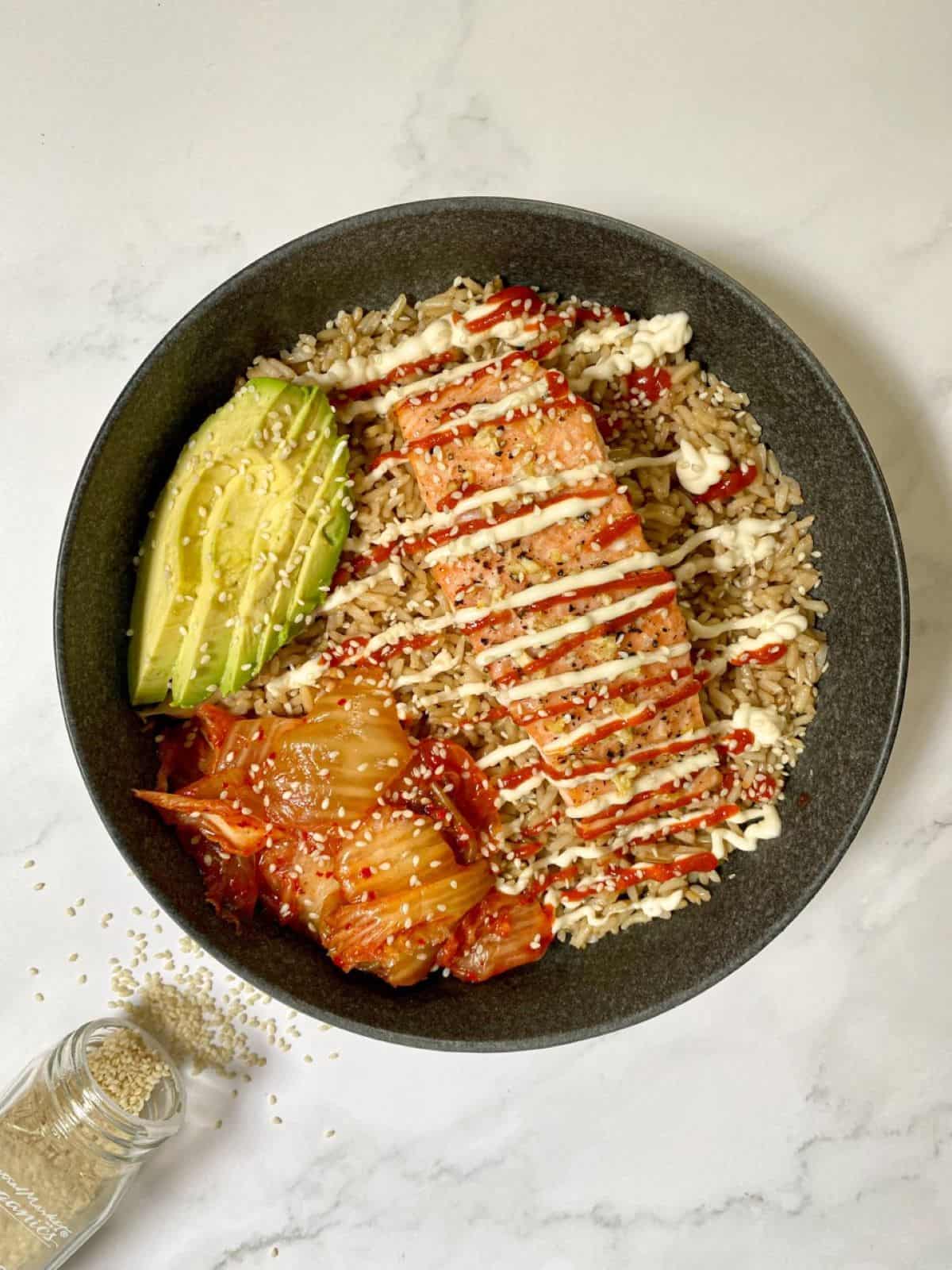 Spicy Salmon Bowl with Kimchi and Avocado sprinkled with sesame seeds.