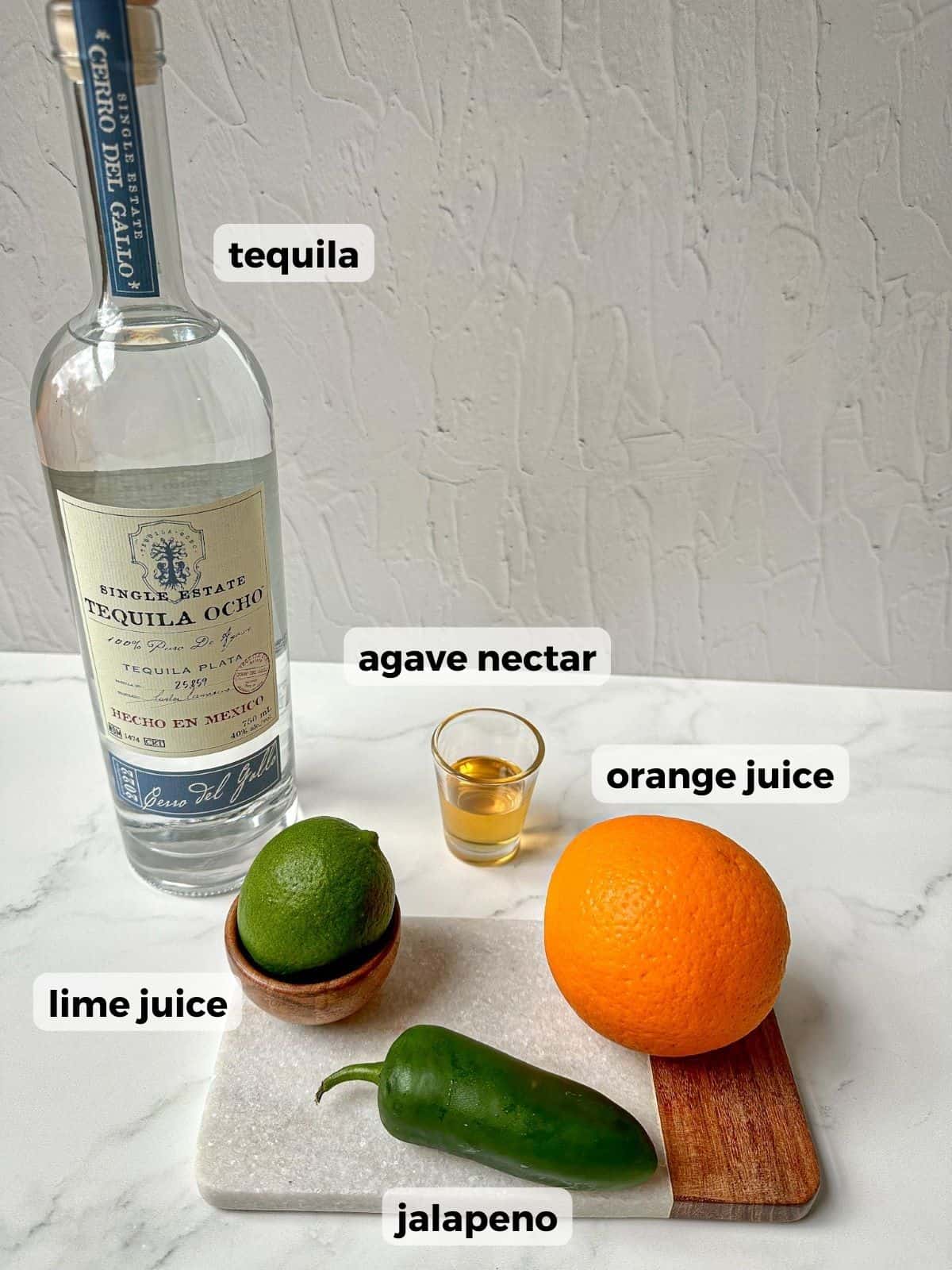 Ingredients needed to make this margarita include: a bottle of tequila, fresh lime juice, fresh orange juice, jalapeno slices, and agave nectar.
