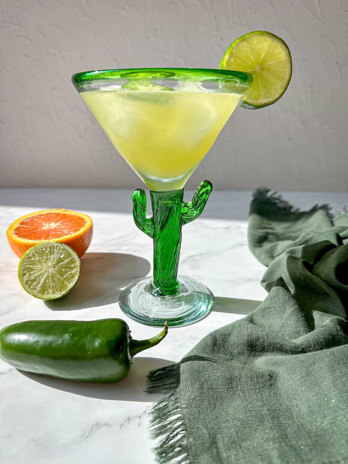 A skinny margarita garnished with a lime wedge in a green cactus shaped glass.