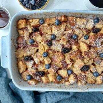 Brioche French toast casserole in a baking dish topped with fresh berries.