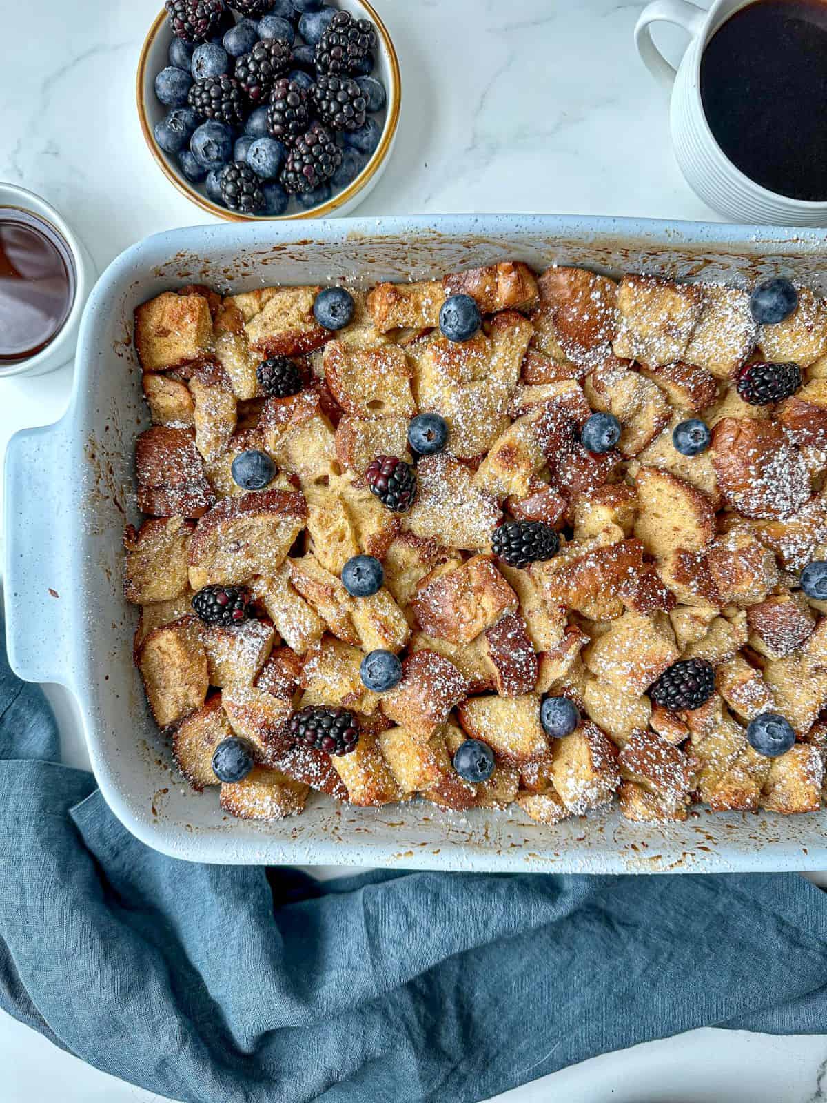 Brioche French toast casserole in a baking dish topped with fresh berries.