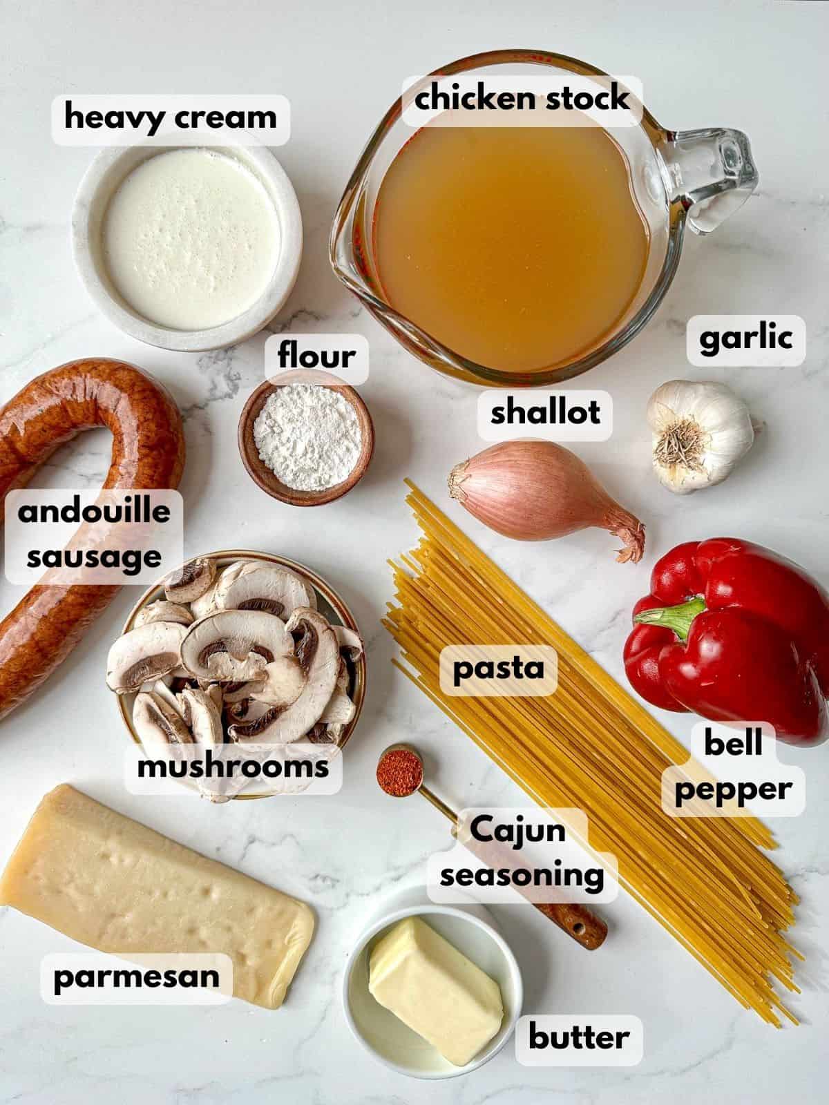 Ingredients needed to cook Cajun spaghetti: pasta, andouille sausage, red bell pepper, mushrooms, garlic, heavy cream, parmesan cheese, and Cajun seasonings.