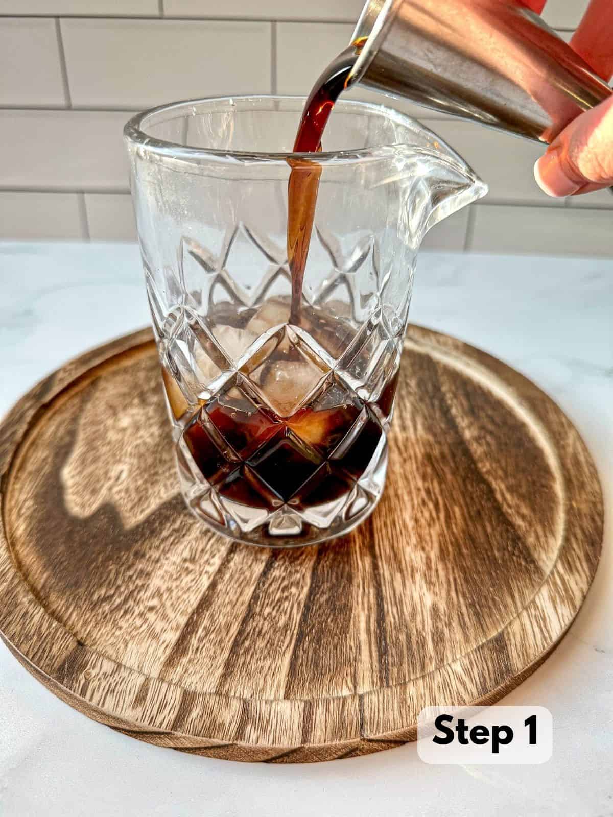 Black cold brew coffee being poured into a cocktail mixing glass.