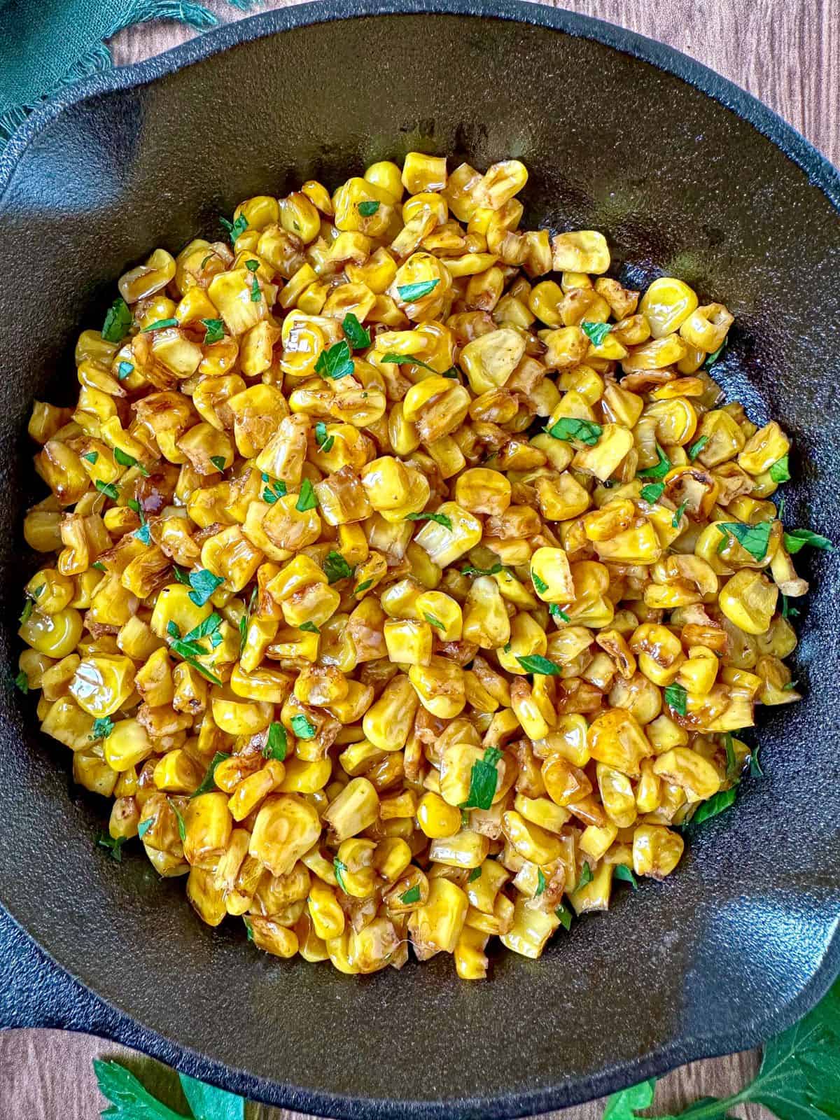 Charred corn in cast iron skillet topped with parsley.