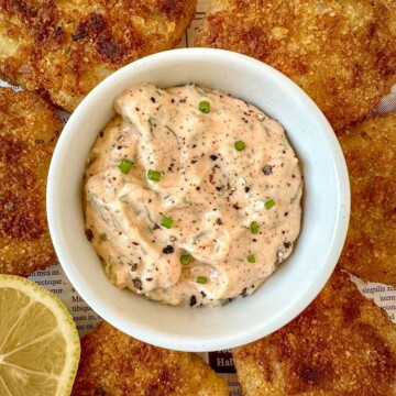 Homemade Cajun tartar sauce in a bowl surrounded by fried fish.