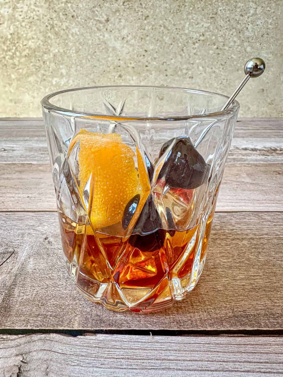 Brown sugar old fashioned in a rocks glass with a cherry and orange peel garnish.