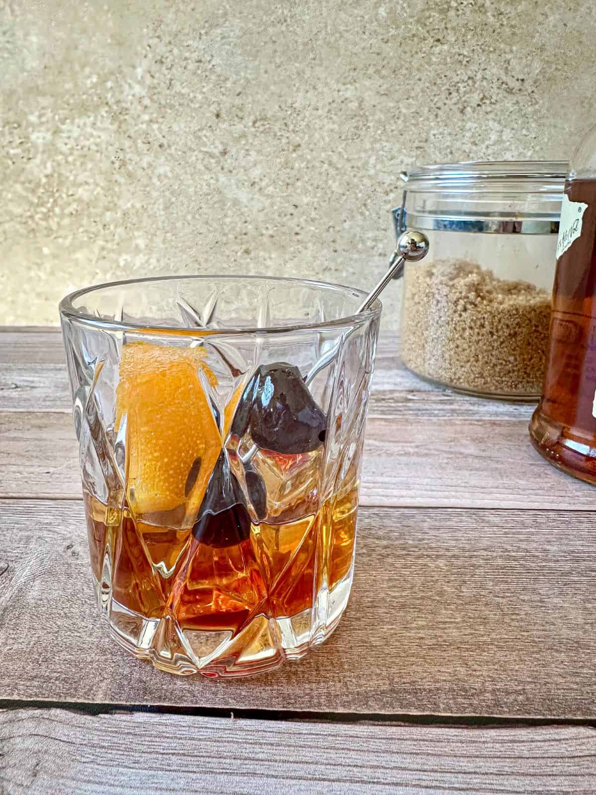 Brown sugar old fashioned in a rocks glass with a cherry and orange peel garnish.
