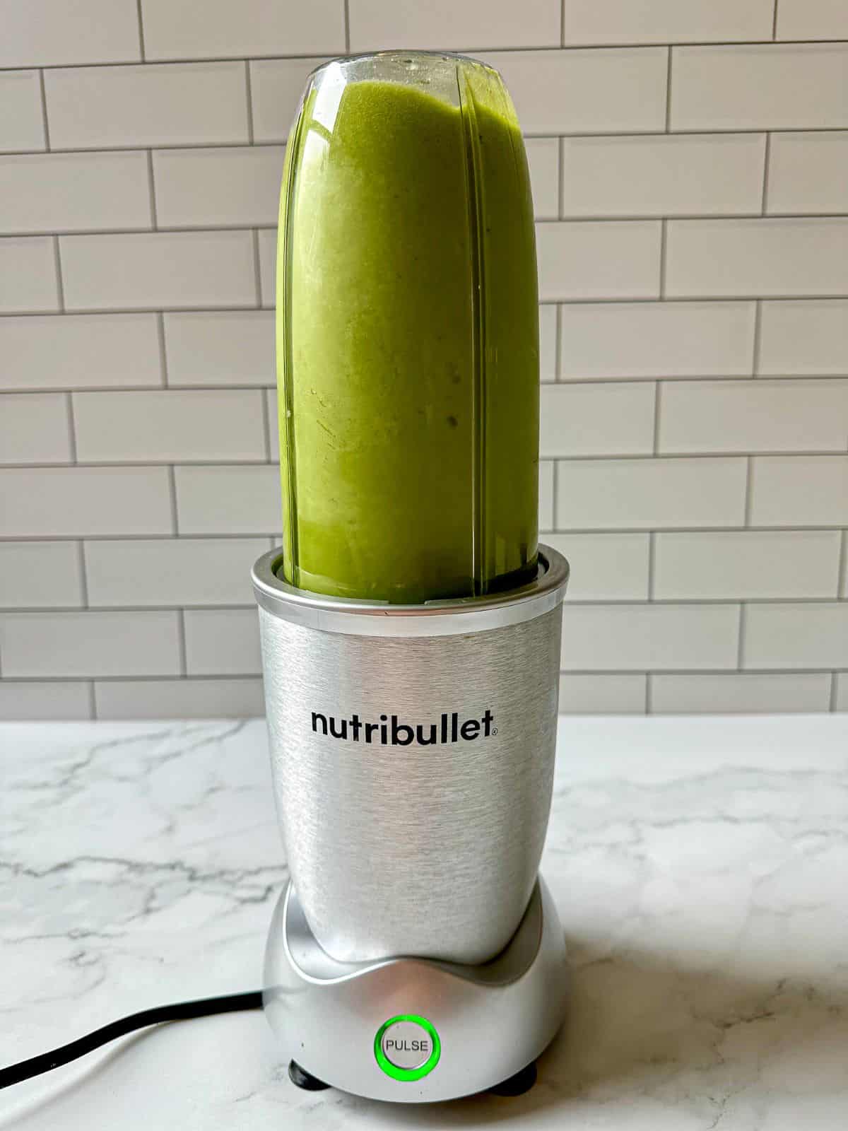 A green smoothie blending in a blender.