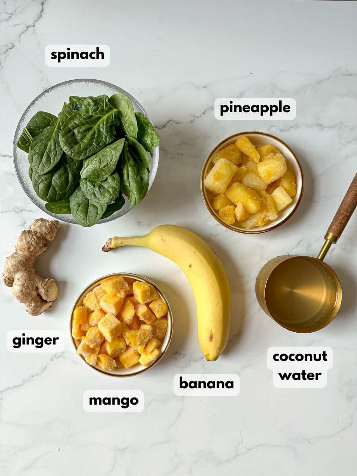 Ingredients need to make a detox island green smoothie are on a marble countertop.