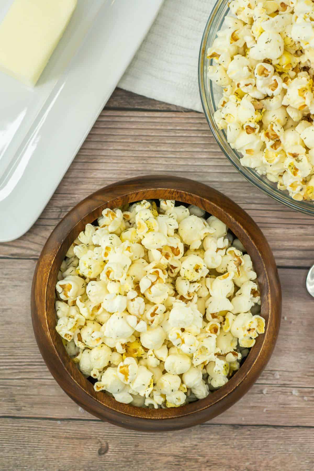 Two bowls of salt and vinegar seasoned popcorn on a wooden table.