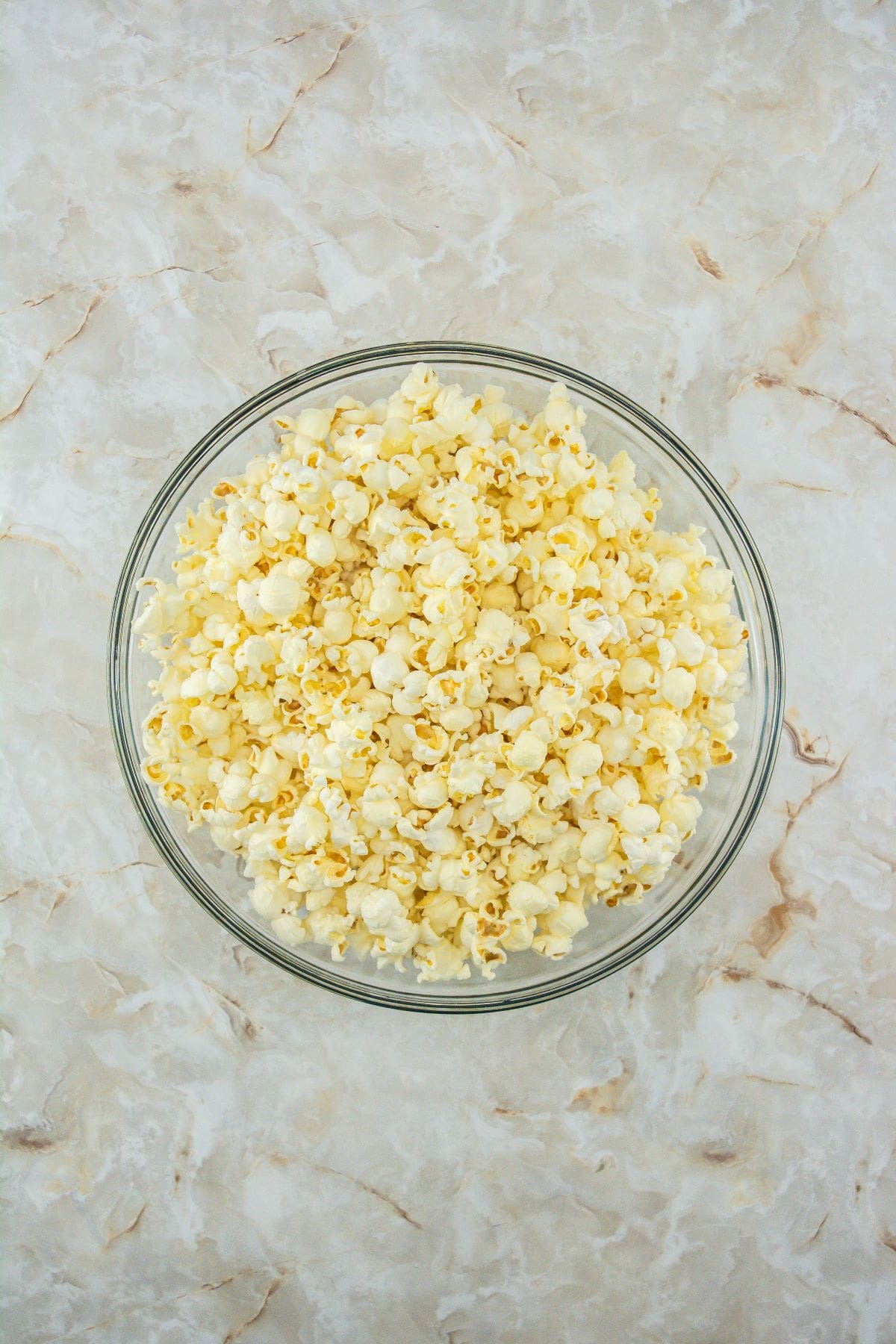 A bowl of freshly popped popcorn on a marble countertop.