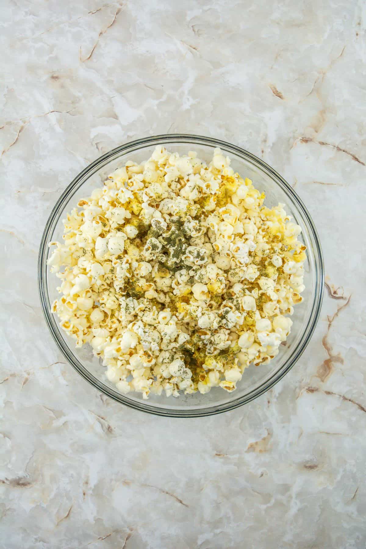 Popcorn sprinkled with dill and salt and vinegar popcorn seasoning.