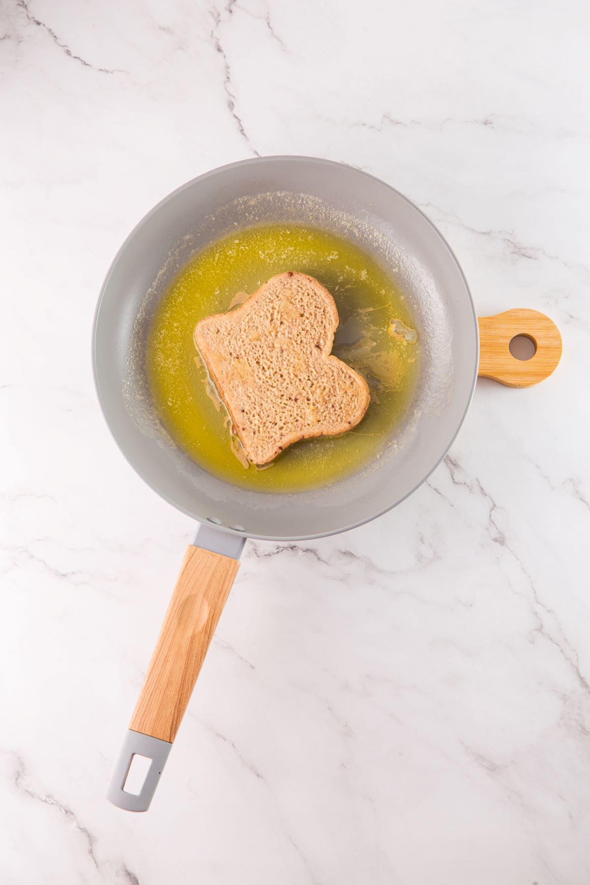 Melted butter in a skillet with a slice of bread.