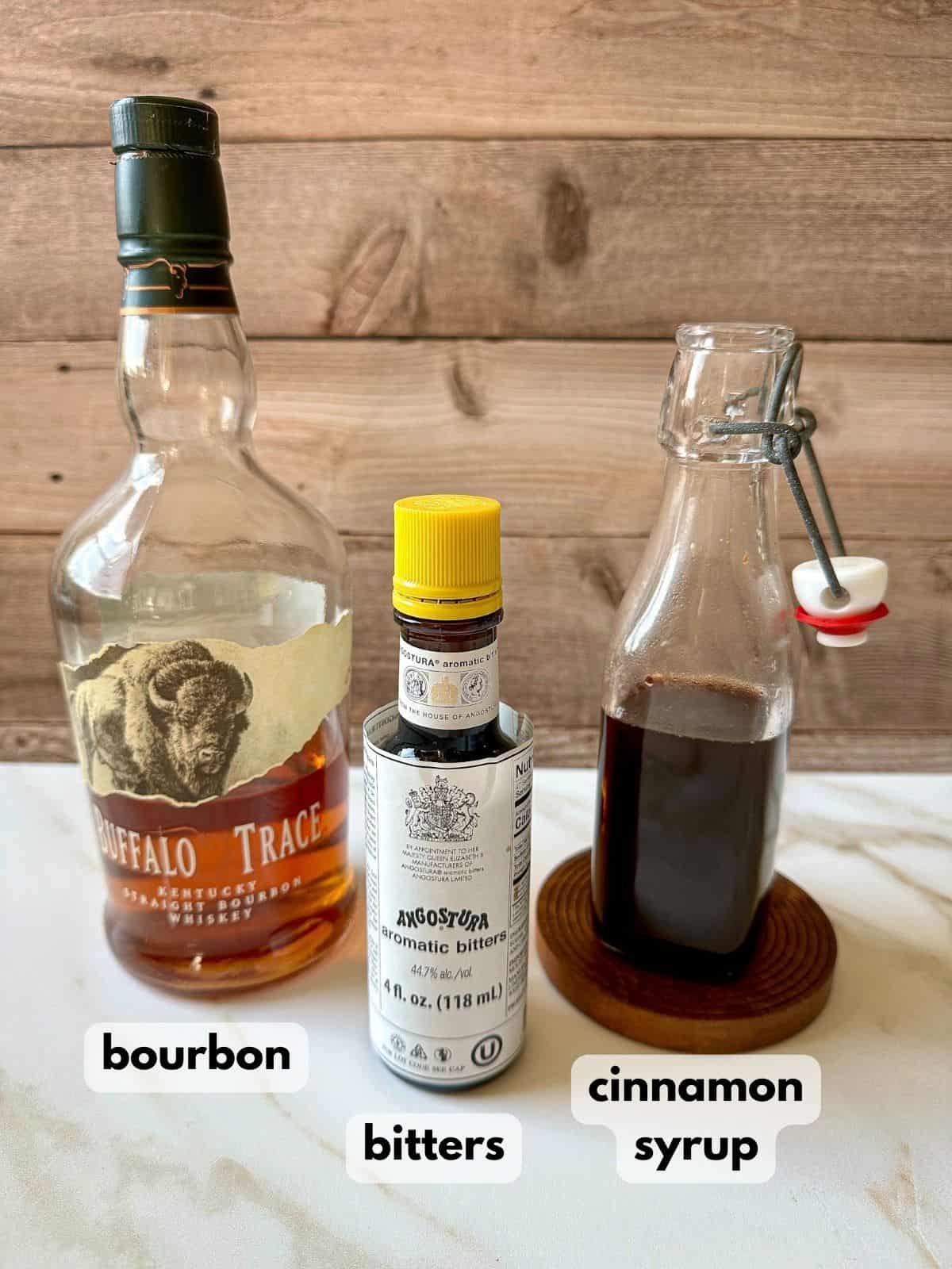 A bottle of bourbon, aromatic bitters, and cinnamon syrup.