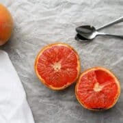 A grapefruit cut in half with two spoons.