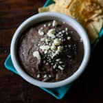 Black bean dip in a bowl with cotija cheese sprinkled on top.