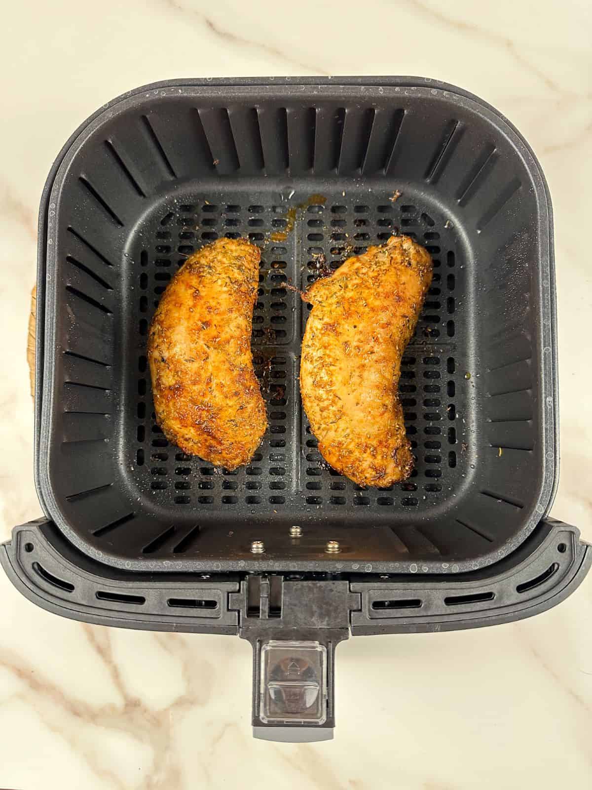 Cooking turkey tenderloin in air fryer basket.