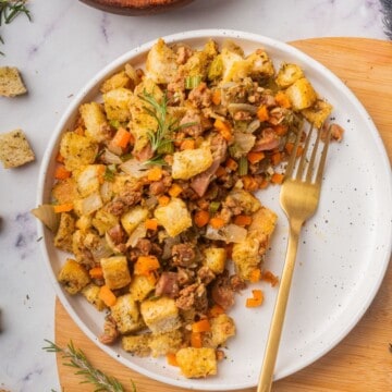 Stovetop sausage stuffing on a white plate with a fork.