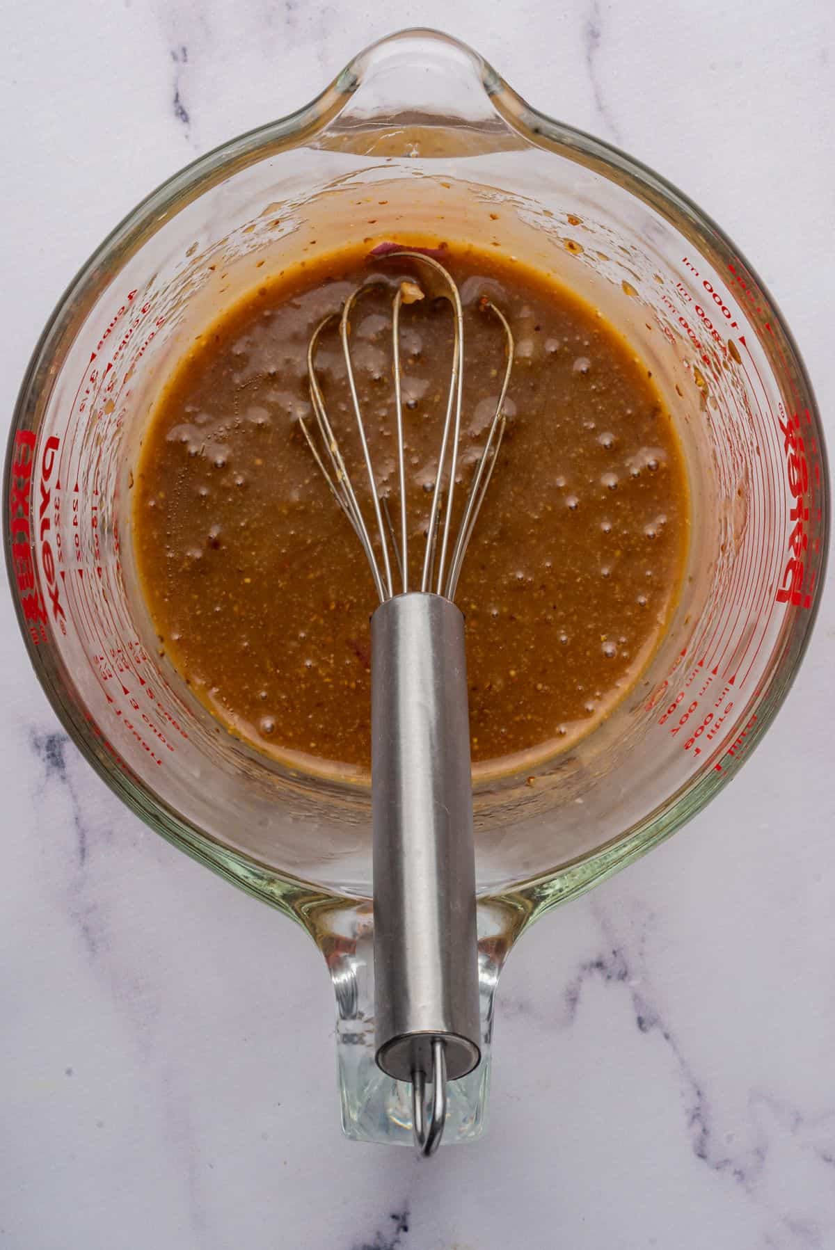 Maple balsamic vinaigrette in a mixing bowl with a whisk.