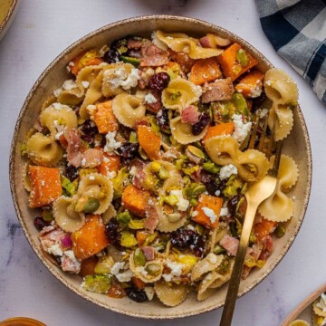 Fall pasta salad with roasted vegetables in a bowl with a gold fork.